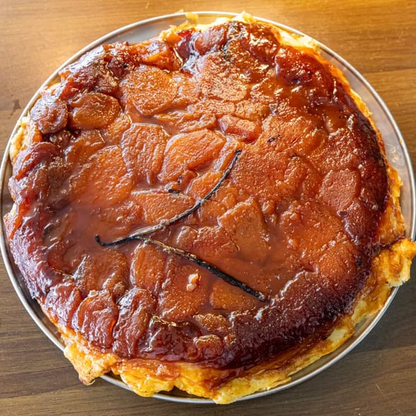 Close-up of a golden-brown Tarte Tatin with caramelized apples and vanilla bean pods.