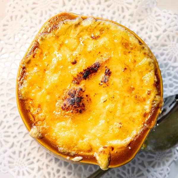 Overhead view of a bowl of French onion soup with melted, bubbly, golden-brown cheese.
